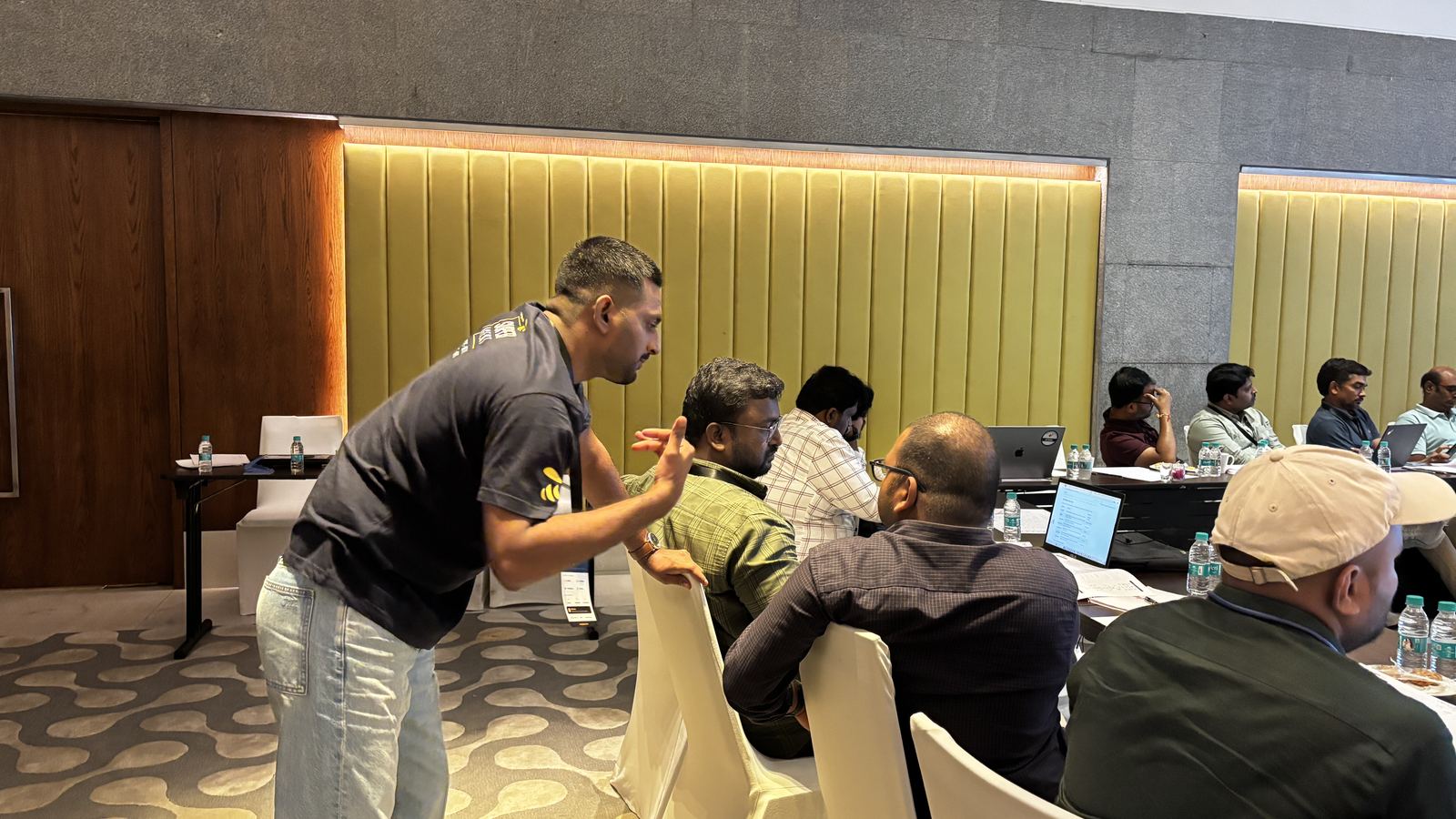 A host helping two attendees at their seats during the hands-on session in Hyderabad